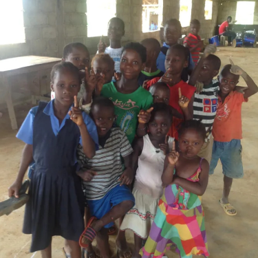 Children in group holding index finger up